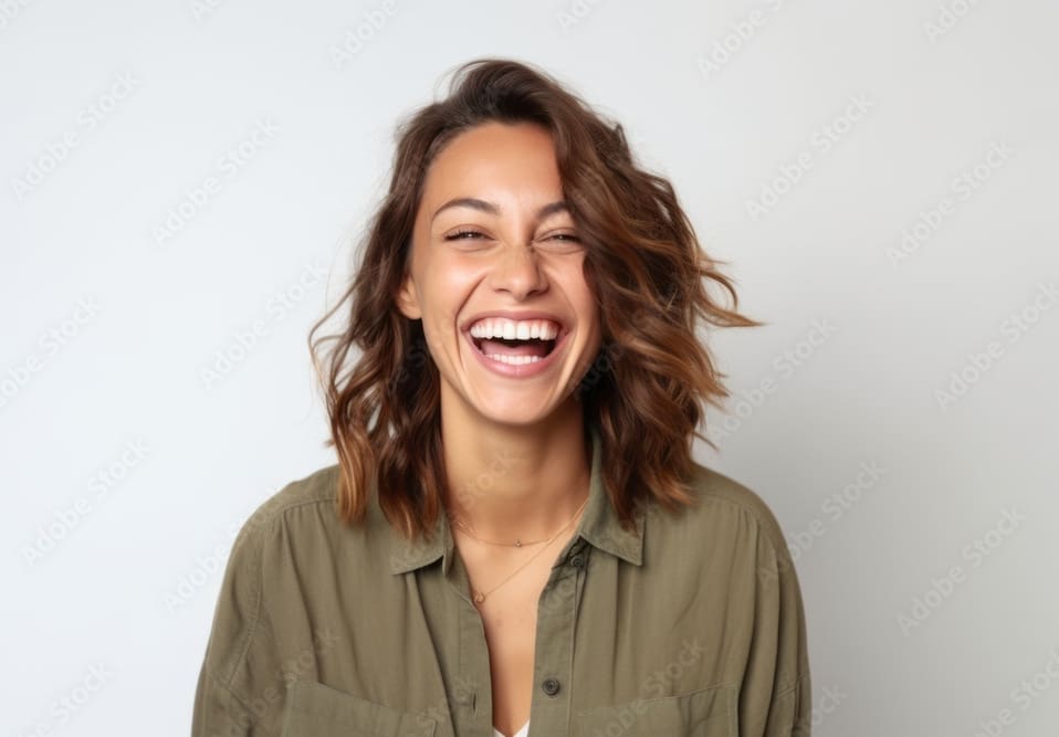 A woman with brown hair is smiling and laughing.