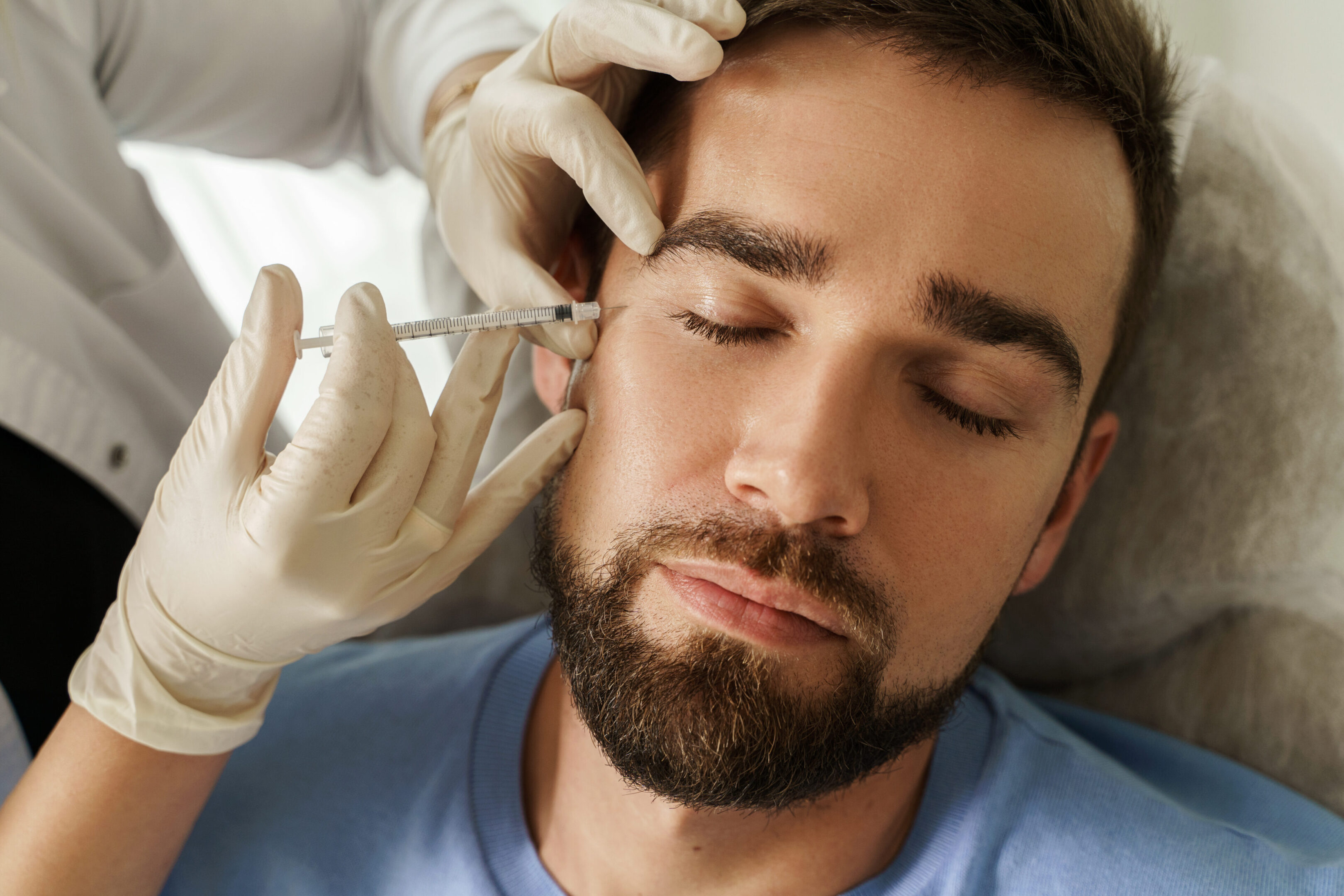 A man getting his face waxed by an esthetician.